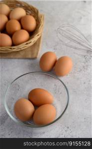 Vertical image with Selective focus three eggs in glasses bowl, blurred eggs in wicker basket and on the floor, preparing preparing for cooking food or dessert, copy space 