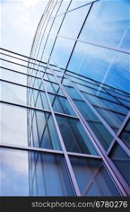 vertical imgage of facade of modern glass blue office and sky with clouds reflected