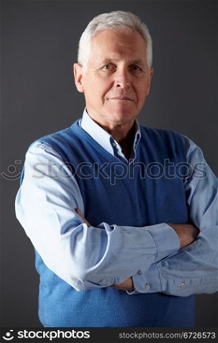 vertical,indoors,studio shot,portrait,black background,white hair,shirt,pullover,sleeveless,blue,arms folded,serious,half length,front view,looking at camera,shadow,people,one person,male,man,caucasian,adult,70s,seventies,senior,older,mature,retired,retirement