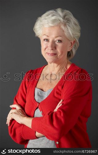 vertical,indoors,studio shot,portrait,black background,white hair,shirt,red,cardigan,casual clothing,arms folded,smiling,half length,front view,looking at camera,people,one person,female,woman,caucasian,adult,60s,sixties,senior,older,mature,retired,retirement