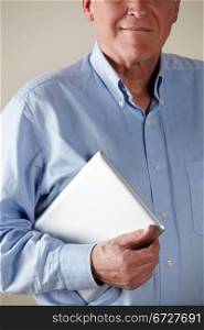 vertical,indoors,studio shot,white background,holding,computer,tablet,technology,surfing,browsing,wireless,internet,white hair,casual clothing,blue,shirt,smiling,confident,front view,cropped,people,one person,male,man,caucasian,adult,70s,seventies,senior,older,mature,retired,retirement,lifestyle,technology