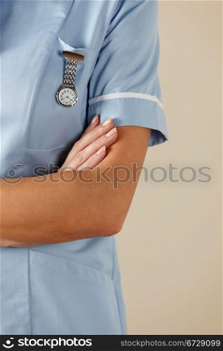 vertical,indoors,studio shot,white background,nurse,health service,hospital,nhs,medical,healthcare,uniform,blue,standing,arms folded,watch,mid section,cropped,people,one person,female,woman,caucasian,adult,30s,thirties,british,english,uk