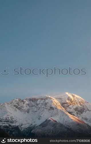 Vertical nature landscape view of snow capped mountain in Karakoram range against clear blue sky. Sunset at Hunza Nagar valley, Gilgit Baltistan, Pakistan. Minimalism concept.