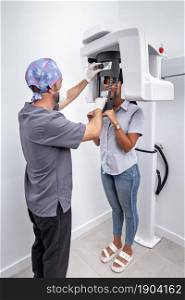 Vertical photo of a dentist adjusting a tooth whitening machine used by a patient in a dental clinic. Verical photo of a dentist adjusting a tooth whitening machine used by a patient