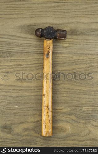 Vertical photo of an old ball peen hammer on aged wood