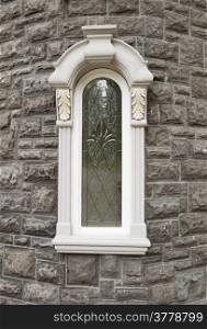 Vertical photo of brand new custom home window with stone structure in background