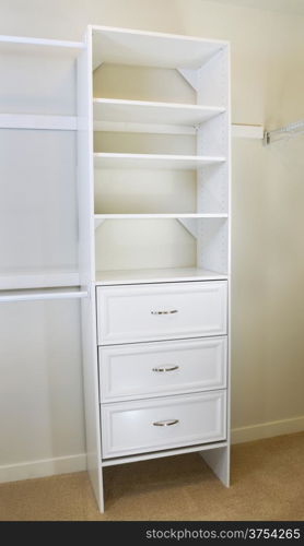 Vertical photo of modern white shelf inside of master bedroom closet residing on carpet