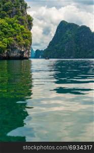 vertical photograph - a picturesque bay, view of a traditional Thai boat in the sea near the rocks
