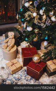 Vertical picture of decorated Christmas tree with balls and many presents under fir tree. Pleasant moments and festive event. Composition of pile with gifts. New Year`s holidays.