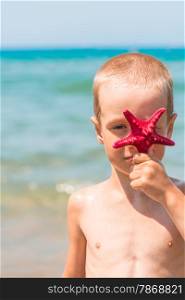 vertical portrait of a boy with a red star on the beach