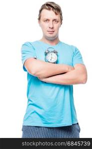 Vertical portrait of a man in pajamas with an alarm clock on whi. Vertical portrait of a man in pajamas with an alarm clock on white background