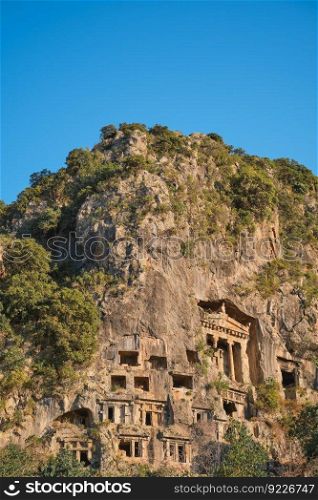 Vertical shot Lycian rock tombs in the city of Fethiye on the Aegean coast of Turkey, Lycian tombs at sunset in spring, the rock-cut tombs of Amyntas rise above the city, travel and vacation time