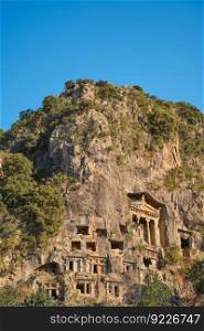 Vertical shot Lycian rock tombs in the city of Fethiye on the Aegean coast of Turkey, Lycian tombs at sunset in spring, the rock-cut tombs of Amyntas rise above the city, travel and vacation time
