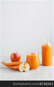 Vertical shot of fresh natural orange carrot juice in glass jar, ripe apple and carrot on white background. Healthy drink and detox.