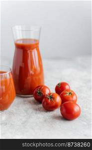 Vertical shot of fresh red tomato juice in glass, red fresh raw tomatoes near on white background. Making ketchup. Organic drink