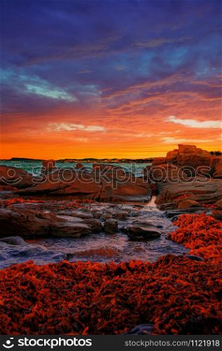 Vertical shot of rock formations in the middle of the sea during a breathtaking sunset