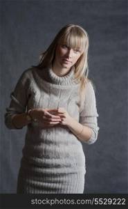 Vertical shot of the long haired blonde. Portrait of elegant young woman in a jumper on a dark background