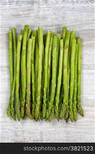 Vertical top view of a pile of asparagus on rustic white wood