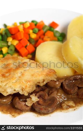 Vertical view of a meal of stewed kidneys topped with suet crust pastry and served with boiled potatoes and mixed vegetables
