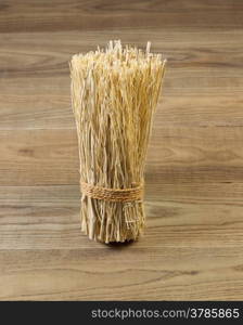 Vertical view of a tied bundle of straw on rustic wood