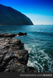 Vertical vivid stony beach tidal waves with ship landscape background. Vertical vivid stony beach tidal waves with ship landscape backg