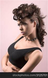 very attractive fashion woman with brown hair and crative hair-style wearing dark top and posing on pink