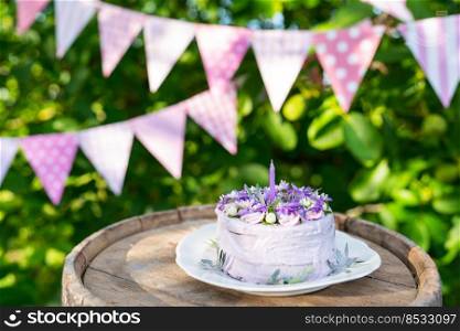 Very beautiful bento cake with purple, veri peri, matthiola flowers with green leaves, candles in the cake on the background of pink flags. Birthday. Horizontal photo. Very beautiful bento cake with purple, veri peri, matthiola flowers with green leaves, candles in the cake on the background of pink flags. Birthday. Horizontal photo.