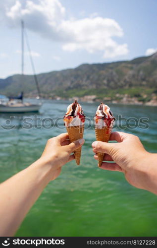 Very beautiful promenade of the Bay of Kotor, Montenegro. Loving couple holding colorful ice cream on the background of the Bay of Kotor. Very beautiful promenade of the Bay of Kotor, Montenegro. Loving couple holding colorful ice cream on the background of the Bay of Kotor.