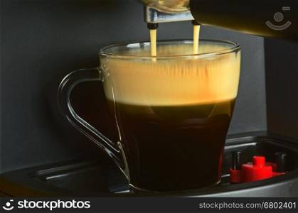 Very close view on coffe machine pouring espresso in the interesting, atmospheric light, with clearly visible, slightly not sharp rivulets pouring coffee and a foam on its surface Horizontal view.&#xA;