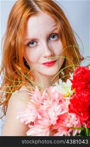 Very closeup shot of the redhead with bunch of flowers in studio on white