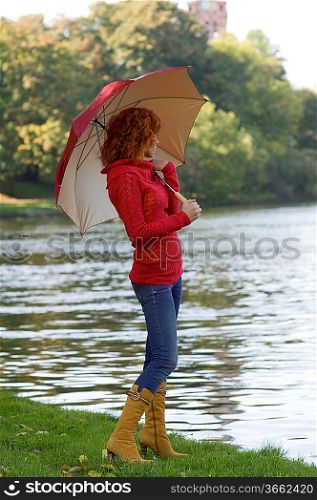 very cute girl looking river with colored umbrella and red pullover