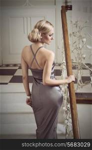 very cute woman , in evening dress going up stair in elegant indoor ambient, she has hair style . vintage color