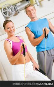 Very fit couple in a gym exercising with tube equipment doing power gymnastics