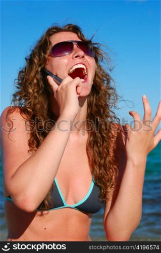 very happy beautiful woman talking by phone near the sea