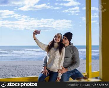 Very Happy Couple In Love Taking Selfie On The Beach in autmun day. Gorgeous couple taking Selfie picture