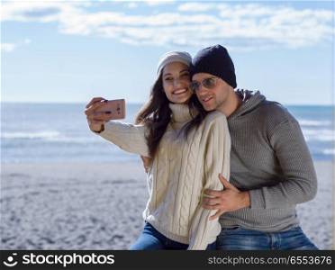 Very Happy Couple In Love Taking Selfie On The Beach in autmun day. Gorgeous couple taking Selfie picture
