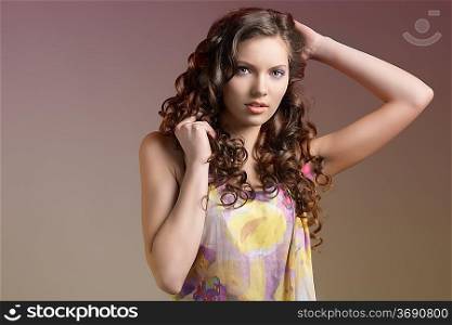 very nice cute young girl with summer colorful dress on dark background. she ha curly hair