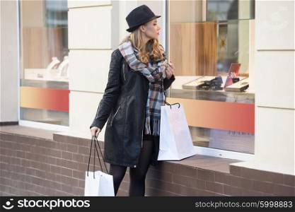 very nice young blond woman , stop and look at window shop during her walking , in the winter sales