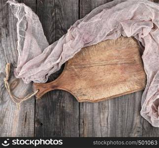 very old brown cutting board with a handle on a wooden plank background, empty space, top view