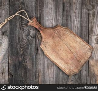 very old brown cutting board with a handle on a wooden plank background, empty space