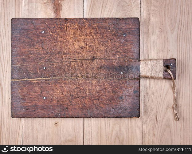 very old brown square cutting board with a handle on a wooden plank background, empty space