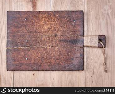 very old brown square cutting board with a handle on a wooden plank background, empty space