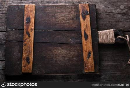 very old brown square cutting board with a handle on a wooden plank background