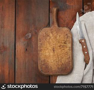 very old empty wooden rectangular cutting board and knife, top view, brown wooden background