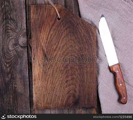 very old empty wooden rectangular cutting board and knife, top view, gray wooden background