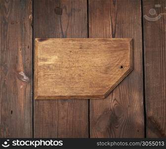 very old empty wooden rectangular cutting board, top view, brown wooden background