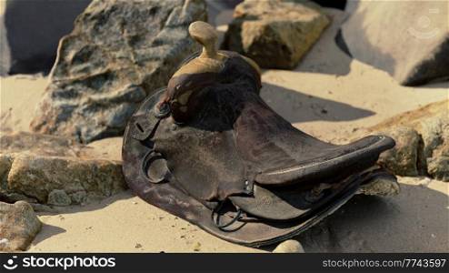 very old horse saddle on sand beach