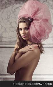 very pretty brunette girl wearing stylish big tulle accessory in the hair, posing naked and covering her breast