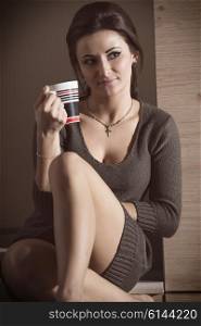 very pretty brunette woman with short dress is sitting in kitchen and drinking a cup of tea of coffee