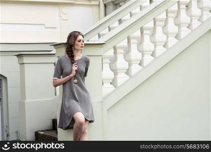 very pretty lady posing in fashion outdoor portrait wearing elegant gray dress and lovely braid hair-style